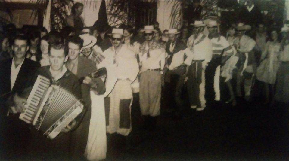 1972, festa junina ou baile caipira. Em um salão iluminado por lâmpadas de Aladim, uma turma de Araçazinho apresentamdo danças típicas. 